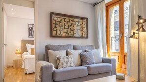 A modern living room with a grey sofa, a wooden coffee table, and a framed abstract artwork on the wall. - Cozy Apartment for Two in Alcalá Area (Madrid)