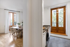 Eine moderne Küche mit einem großen Fenster, einem Essbereich mit Tisch und Stühlen sowie Blick ins Freie.