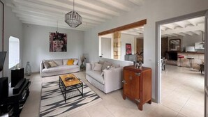 A spacious living room with a sofa, coffee table, and a cabinet. There is a television and a painting on the wall. - Entre vignes et océan (Jau-Dignac-et-Loirac)