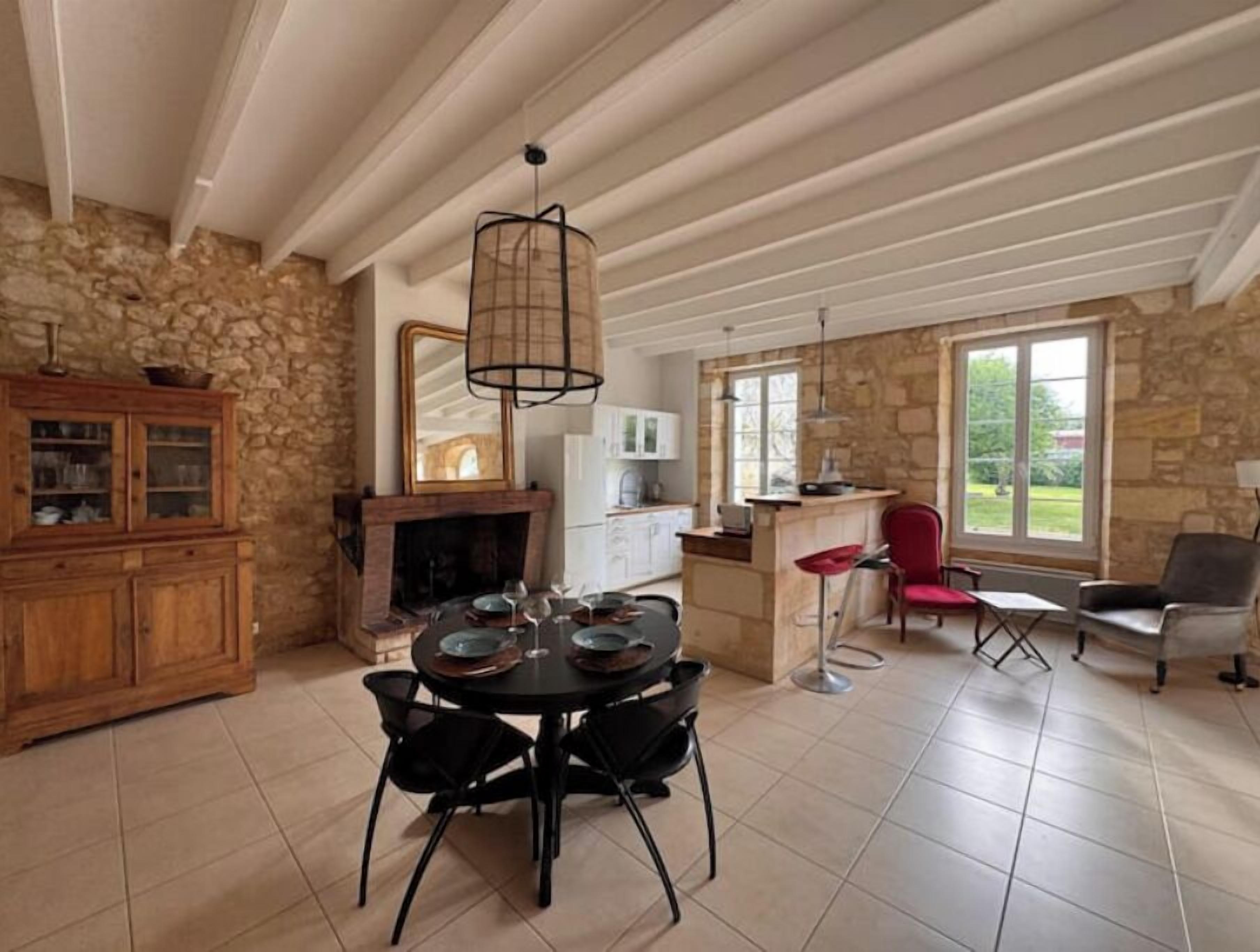 A spacious dining area with a stone fireplace, a wooden cabinet, and a dining table with chairs.