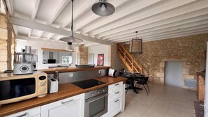 A modern kitchen with a stone wall, wooden counter, and a built-in oven. - Entre vignes et océan (Jau-Dignac-et-Loirac)