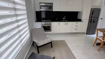 A modern kitchen with white cabinets, a black countertop, and stainless steel appliances.