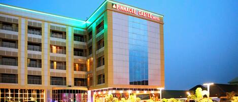 A hotel with multiple floors and a large parking lot filled with cars.