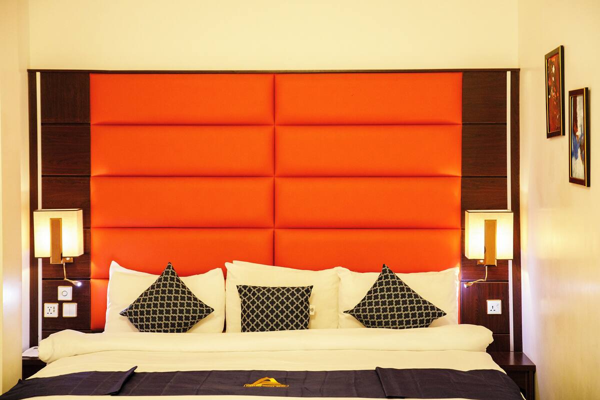 A bed with a headboard, pillows, and bedside lamps.