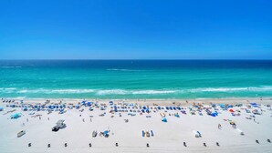 Ein Strand mit zahlreichen Liegestühlen und Sonnenschirmen, einem klaren blauen Himmel und dem Ozean.