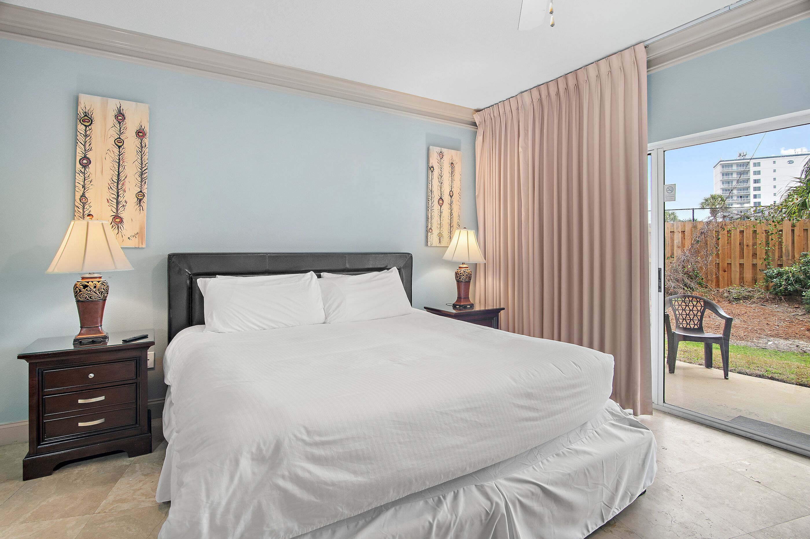 Une chambre avec un grand lit, deux tables de chevet avec des lampes et une vue sur une cour intérieure, accessible par une porte-fenêtre coulissante.
