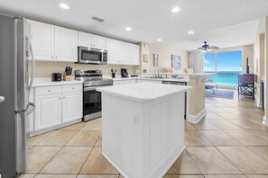 A modern kitchen with white cabinets, stainless steel appliances, and a large island. - ⛱️Beachfront | 5 Pools | Majestic Beach Towers 2-305⛱️ (Panama City Beach)