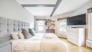 Um quarto moderno com uma cama grande, uma televisão, uma estante e vista para o exterior.