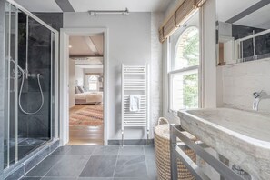 A modern bathroom with a glass shower enclosure, a white towel rack, and a large window providing natural light. - Experience London in amazing reconverted Gin house (London)