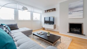 Ein modernes Wohnzimmer mit einer Couch, einem Couchtisch, einem Fernseher und einem Kamin.