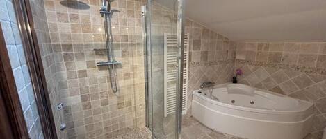 A modern bathroom with a glass-enclosed shower, a freestanding bathtub, and tiled walls.