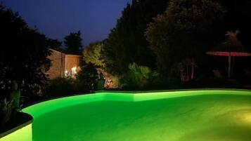 A swimming pool with a curved edge and a green-lit interior.