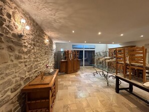 A spacious room with a stone wall, wooden furniture, and a glass table. - Mas Provençal à flanc de colline (Bollène)