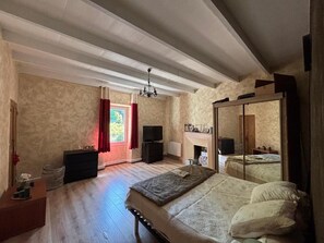 A bedroom with a large bed, a dresser, a TV, and a fireplace. - Mas Provençal à flanc de colline (Bollène)