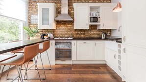 A kitchen with white cabinets, a brick wall, a stove, and a large window. - Modern   Scandi-style 2bed facing Vauxhall Park (Greater London)