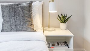 A neatly arranged bedroom with a bed, a bedside table with a lamp, a potted plant, and a window with blinds. - Modern   Scandi-style 2bed facing Vauxhall Park (Greater London)