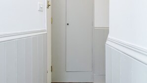 A narrow hallway with white walls and wooden flooring, leading to a closed door. - Modern   Scandi-style 2bed facing Vauxhall Park (Greater London)