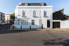 A white building with a corner entrance, large windows, and a garage door. - Modern   Stylish 2bed 2bath close to Kings Road (London)