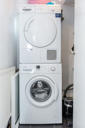 Eine übereinander gestellte Waschmaschine und ein Trockner in einem Waschraum.
