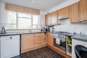 Eine moderne Küche mit Holzausstattung, einem Geschirrspüler, einem Herd und einer Spüle.