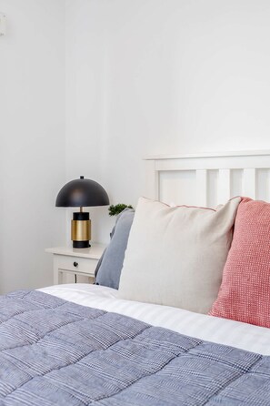 A neatly made bed with a blue quilt, a white pillow, and a red patterned pillow. - Spacious 2bed in top location Holland Park-N Hill (Greater London)