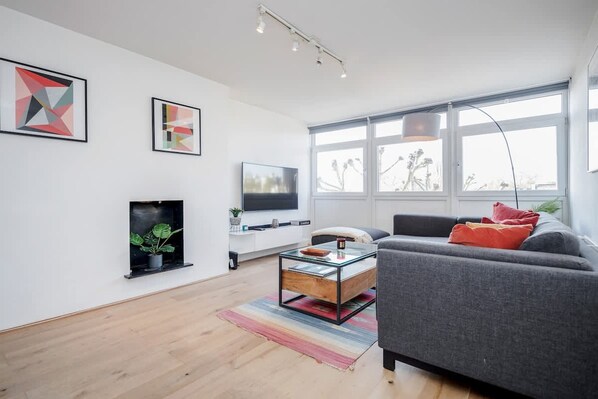 A modern living room with a grey sofa, a glass coffee table, a flat-screen TV, and artwork on the walls. - Spacious 2bed in top location Holland Park-N Hill (Greater London)