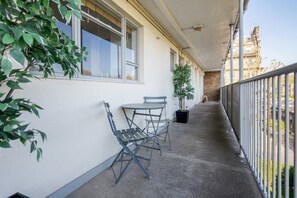 A balcony with a table and chairs, a potted plant, and a view of a building in the background. - Spacious 2bed in top location Holland Park-N Hill (Greater London)