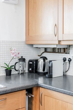 Eine Küche mit Holzausstattung, einer schwarzen Arbeitsplatte, einer Kaffeemaschine, einem Toaster und einem Wasserkocher.