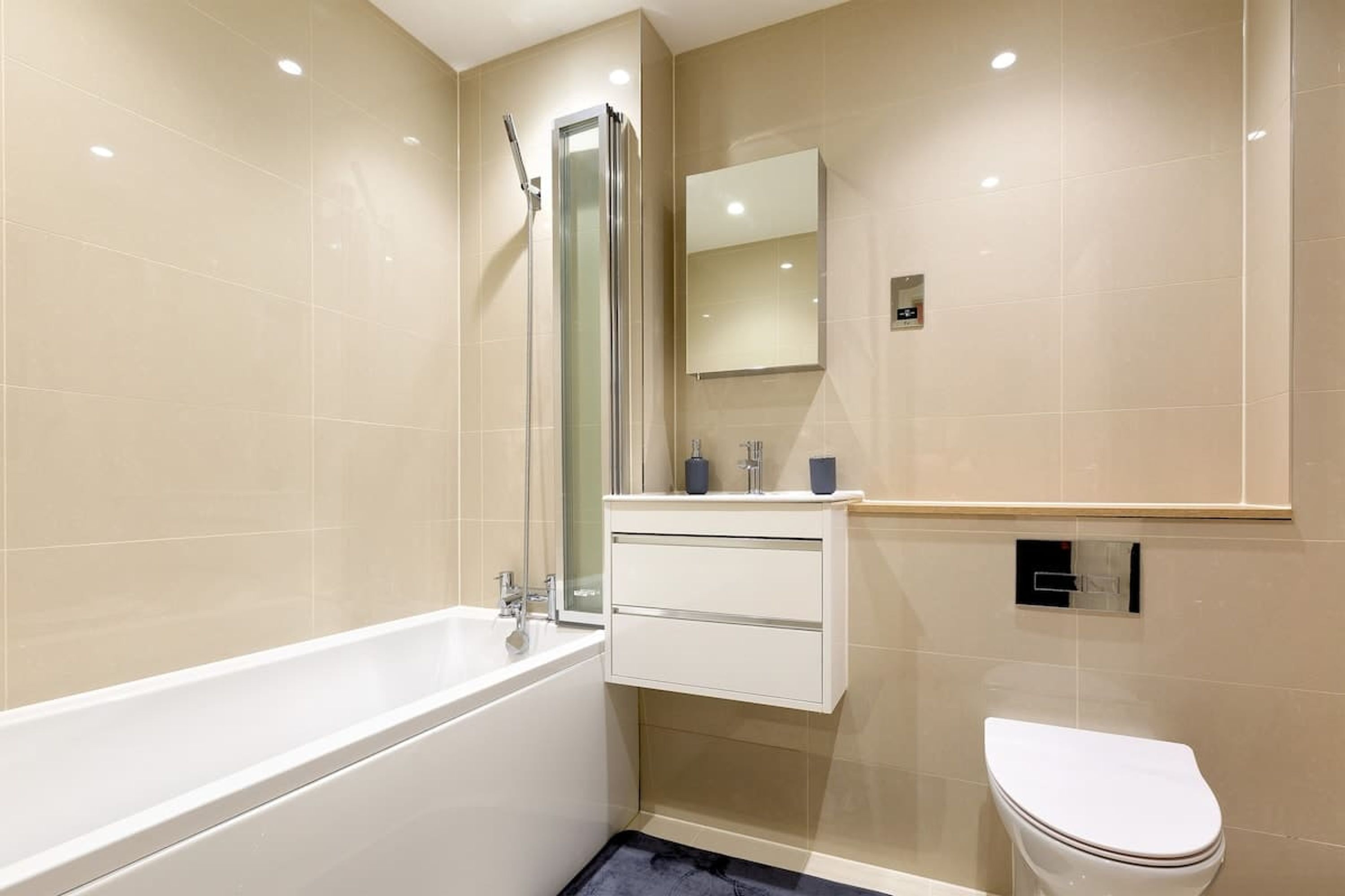 A modern bathroom with a bathtub, a shower, a toilet, and a vanity with a mirror.