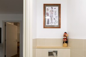 Una obra de arte enmarco que muestra una figura con accesorios sobre una pared, una escultura de madera y una pared con azulejos que incluye un estante empotrado.