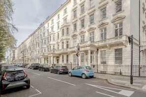 Eine Straße mit parkenden Autos und einem Gebäude im klassischen Stil.