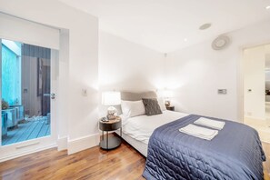 A modern hotel room with a large bed, a bedside table with a lamp, and a view of a balcony. - Spacious   modern 2bed 2 5bath in Pimlico-Victoria (Greater London)