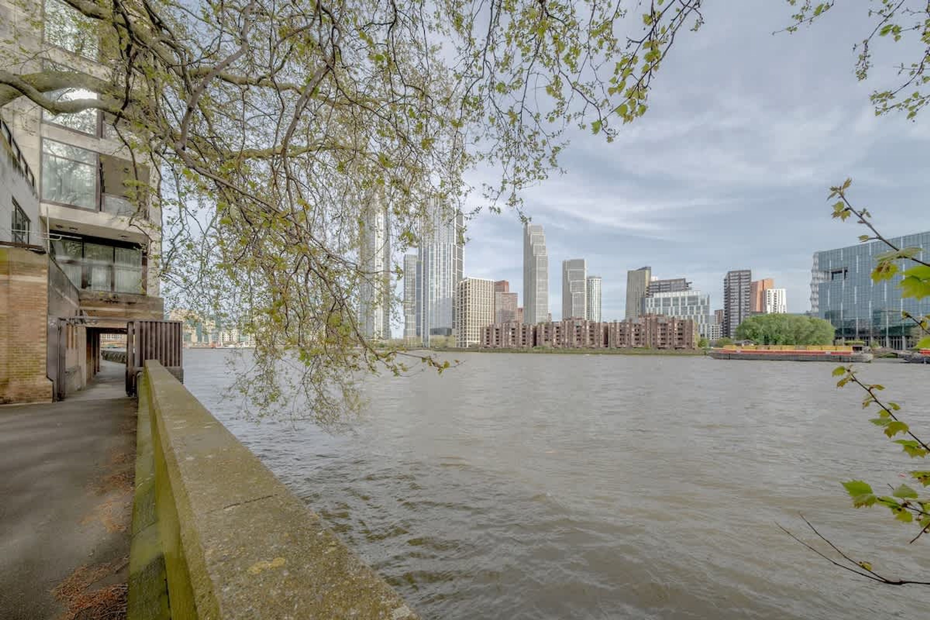 A riverside view with modern buildings and a bridge.