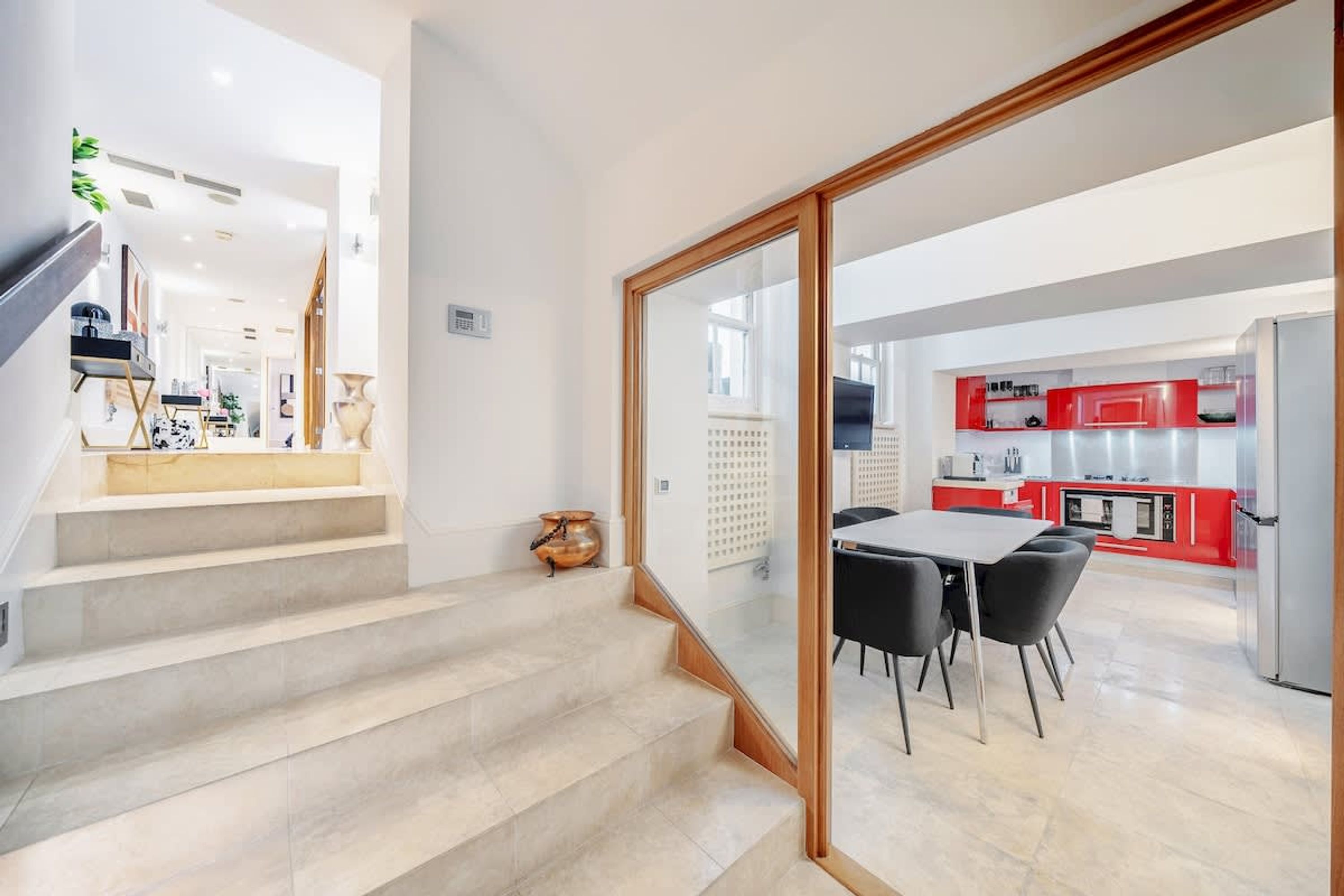A modern kitchen with red cabinets and a dining area with a table and chairs.