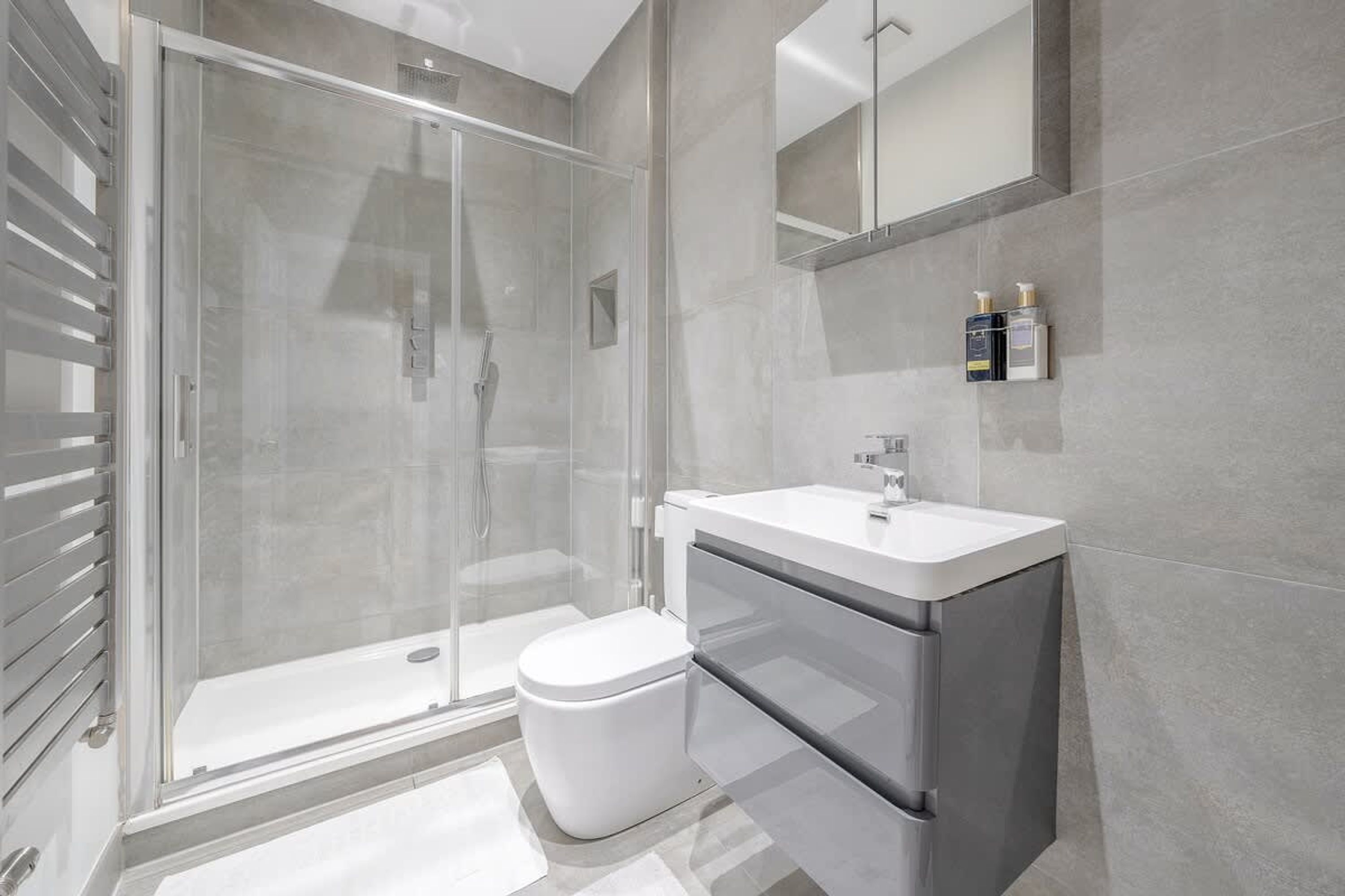 A modern bathroom with a glass shower enclosure, a white toilet, and a vanity with a mirror.
