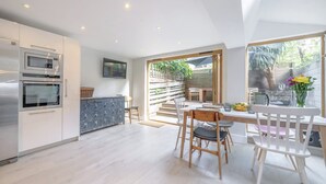 Uma cozinha moderna com eletrodomésticos embutidos, um espaço de jantar com mesa e cadeiras, e vista para o exterior.