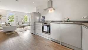 Eine moderne Küche mit Einbauofen, Edelstahlkühlschrank und einer Kaffeestation.