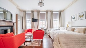 A hotel room with a bed, a desk with a chair, a sofa, and a fireplace. - Unbeatable location in Camden-spacious studio flat (Greater London)