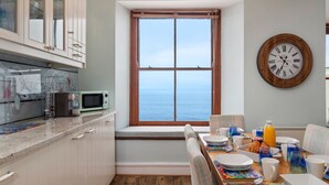 Una cocina con vista al mar, una mesa de desayuno y un reloj de pared.