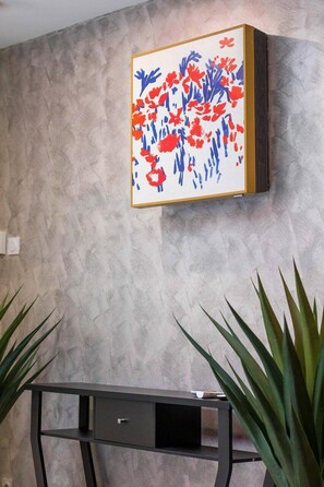 A room with a textured wall, a black desk with a drawer, and a framed abstract painting. - Adresse Secrete Suite Spa Prestige avec Balneo (Dijon)