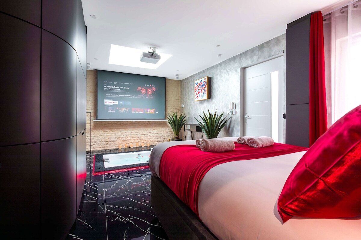 Ein modernes Hotelzimmer mit einem Bett, einem Fernseher, einer Tür und einem roten Vorhang.