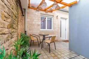 A patio with a brick wall, a window, and a table with chairs. - Adresse Secrete Suite Spa Prestige avec Balneo (Dijon)