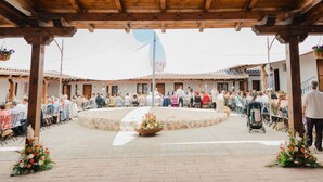 An outdoor covered area with a circular seating arrangement, stone walls, and wooden beams. - SANGHA SPACE. Entire Property, 13 Bedrooms. (Mora)