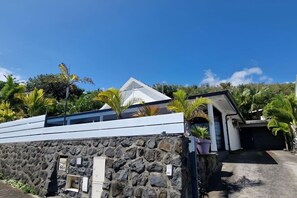 A modern building with a stone wall, a white roof, and a small entrance. - Villa Rêve Austral - Three Bedroom Villa, Sleeps 6 (Saint Pierre)
