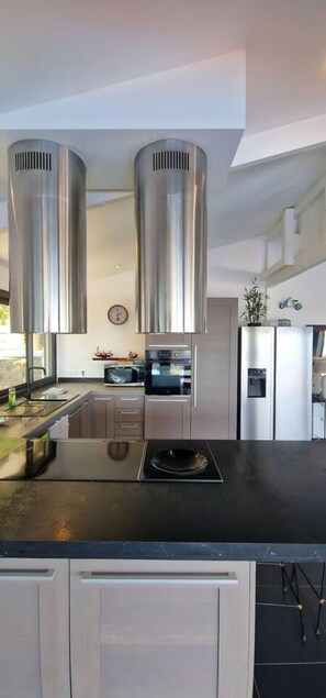 A modern kitchen with stainless steel appliances, a black countertop, and light-colored cabinetry. - Villa Rêve Austral - Three Bedroom Villa, Sleeps 6 (Saint Pierre)