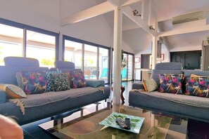 A modern living room with two sofas, a glass coffee table, and large windows. - Villa Rêve Austral - Three Bedroom Villa, Sleeps 6 (Saint Pierre)