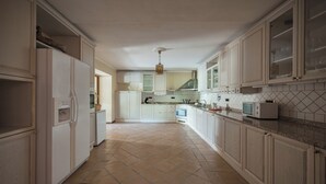 Een ruime keuken met witte kasten, een betegelde vloer en een magnetron.