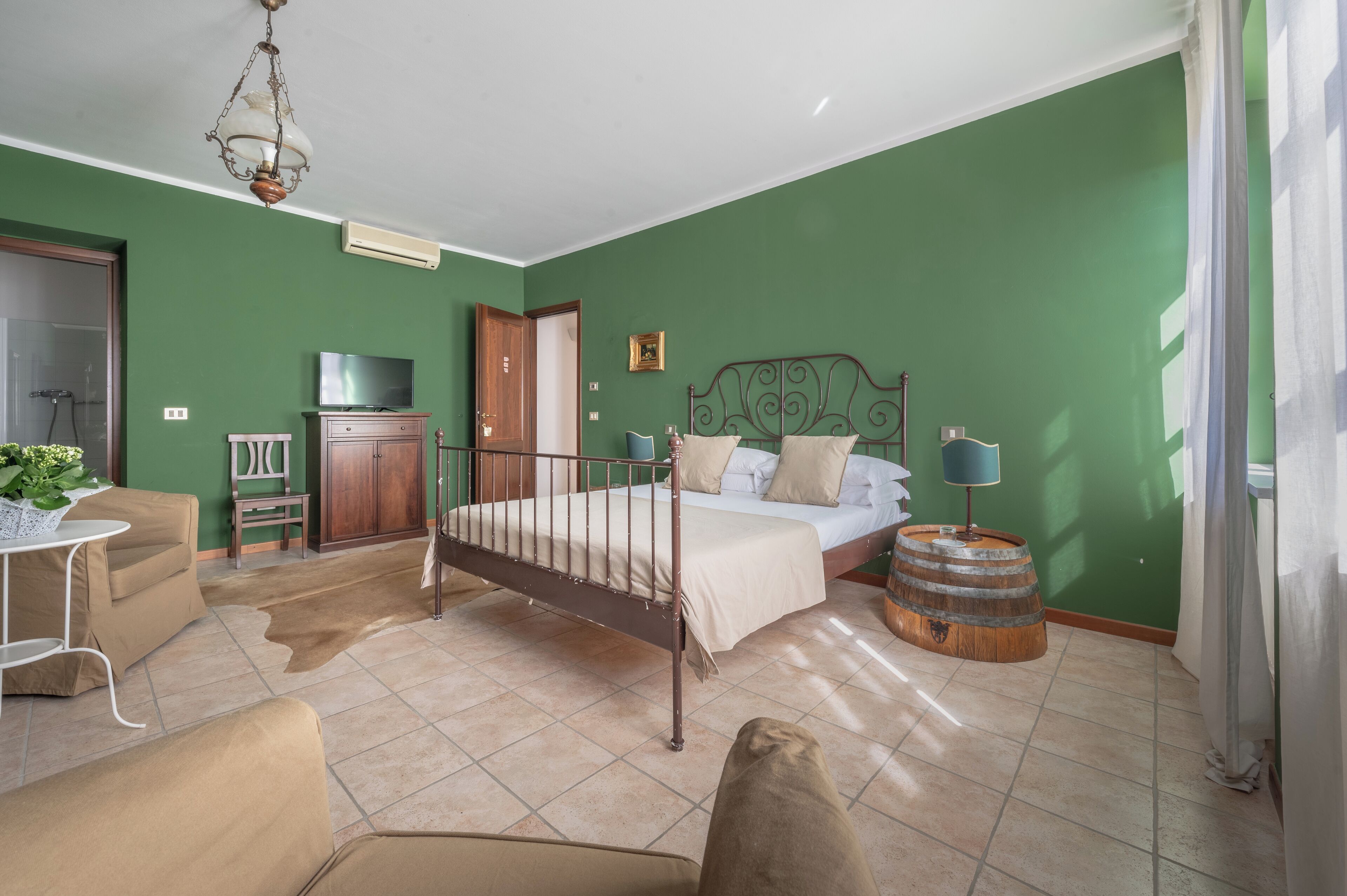 A bedroom with a bed, a television, a wardrobe, a small table, and a chair.