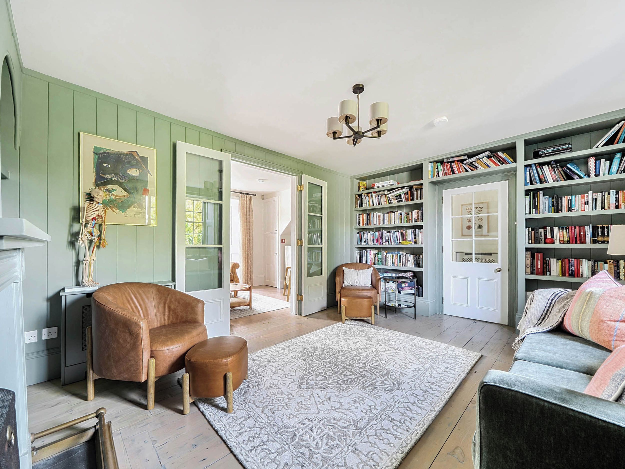 A room with a brown leather chair, a white rug, a bookshelf, and a door leading to another room.
