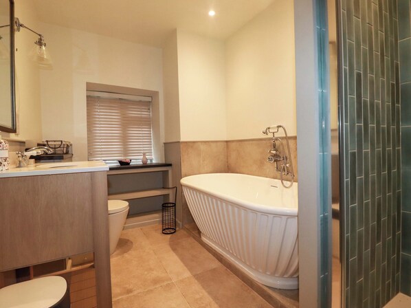 Une salle de bain moderne avec une baignoire sur pieds, des toilettes et un lavabo avec un miroir au-dessus.
